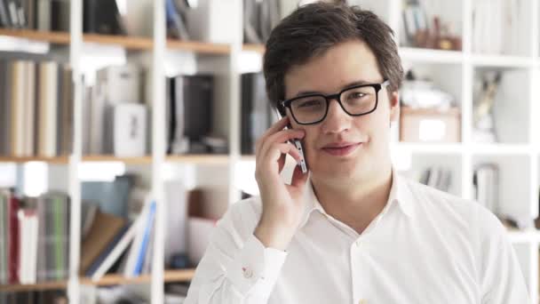 Primer plano de un joven hombre de negocios al teléfono en la oficina — Vídeos de Stock