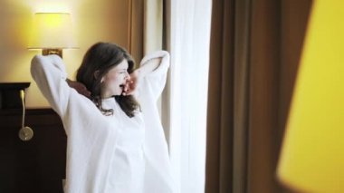 Esneme ve germe bir pencereden bakan genç kadın