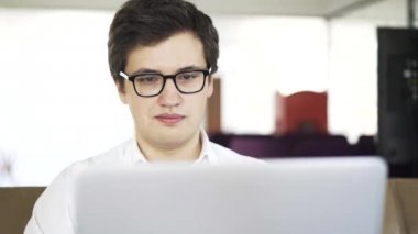 Beyaz gömlekli bir kanepe üstünde laptop üzerinde çalışan genç işadamı yakın çekim
