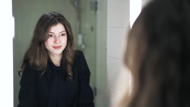 Молода жінка посміхається собі в дзеркало — стокове відео