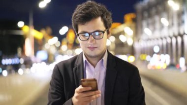 Gözlük web sörf ile telefon, yakışıklı genç işadamı portresi gece