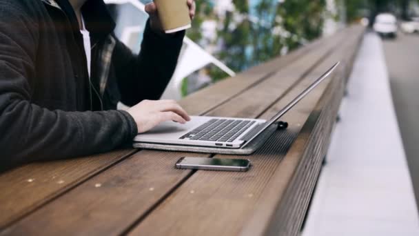 Вид сбоку на человека, работающего на ноутбуке в парке — стоковое видео