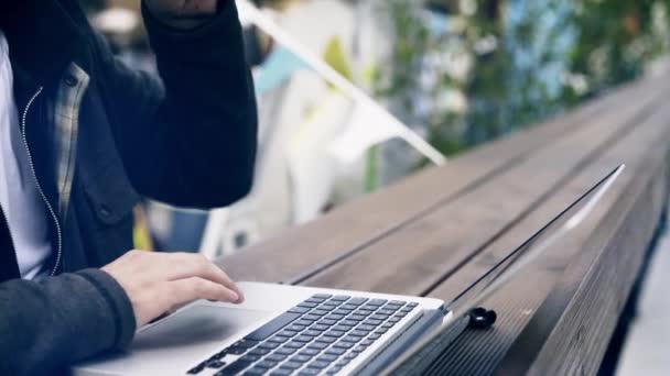Umkippen eines Mannes, der in einem Park an seinem Laptop arbeitet — Stockvideo