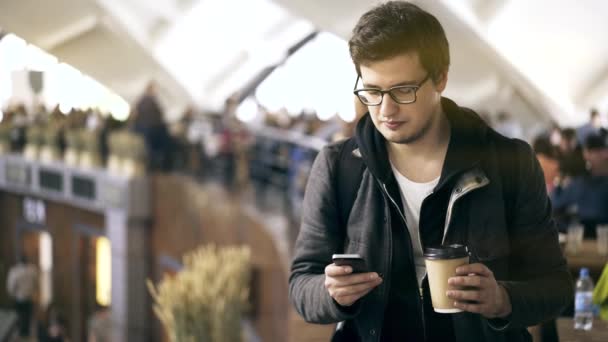 Молодий чоловік з телефоном і кавою на фермерському ринку — стокове відео