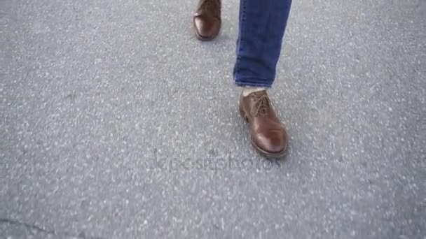 Ноги людини в джинсах і взутті, що йдуть крупним планом — стокове відео