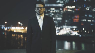 Genç işadamı gözlük. Cityscape akşam arka plan.