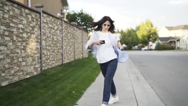 Mujer joven en jeans escuchando la música y bailando en la calle — Vídeos de Stock