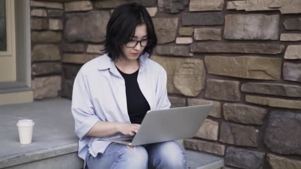 Mujer asiática en gafas de trabajo con un ordenador portátil fuera — Vídeo de stock