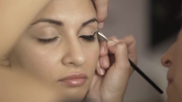 Maquillaje artista aplicar crema tonificante a la zona de los ojos de una chica — Vídeo de stock