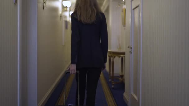 Joven mujer de negocios con un equipaje en el vestíbulo de un hotel — Vídeo de stock
