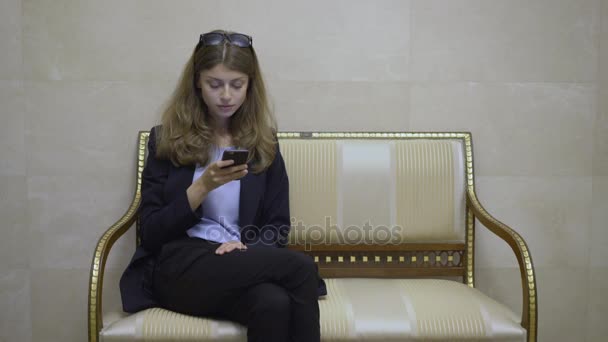 Jeune femme d'affaires dans un hall d'hôtel regardant son écran de smartphone — Video