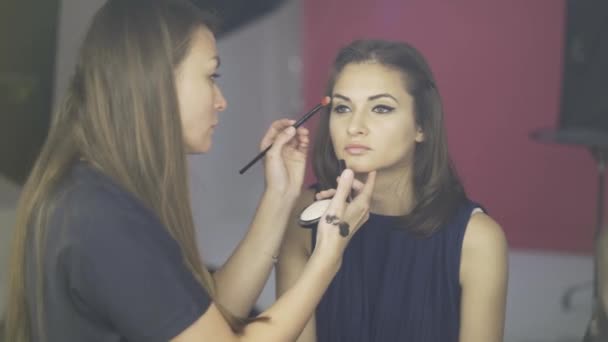 Maquillaje artista aplicando una crema tonificante a la cara de una modelo en un estudio — Vídeos de Stock