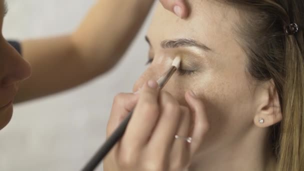 Makeup artist applying bronze shadows to beautiful model s eyelids side view — Stock Video