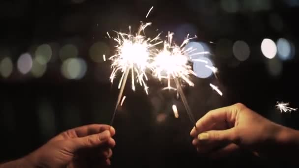 Man and woman s hands holding sparklers at night — Stock Video