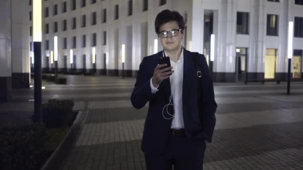 Ung affärsman webbsurfande medan promenader i en natt stad — Stockvideo