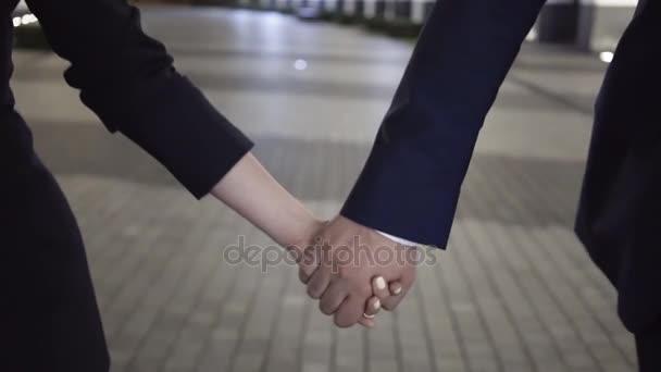 Casal jovem de pessoas de negócios andando em uma cidade noturna de mãos dadas, close-up — Vídeo de Stock