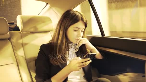 Femme d'affaires sérieuse regardant son smartphone dans une voiture et pensant — Video