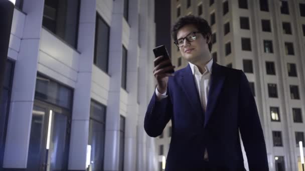 Όμορφος νεαρός επιχειρηματίας για web-surfing σε μια πόλη το βράδυ — Αρχείο Βίντεο