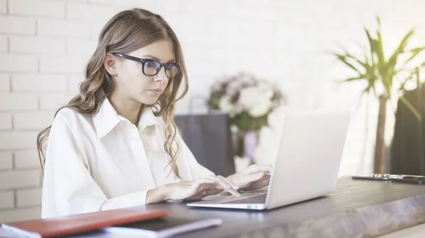 Onu laptop ofiste, yazarak gözlüklü genç güzel bir kadın yan görünüm. — Stok fotoğraf
