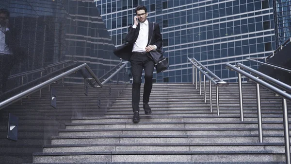 Un hombre de negocios guapo bajando escaleras y conversando por teléfono . — Foto de Stock