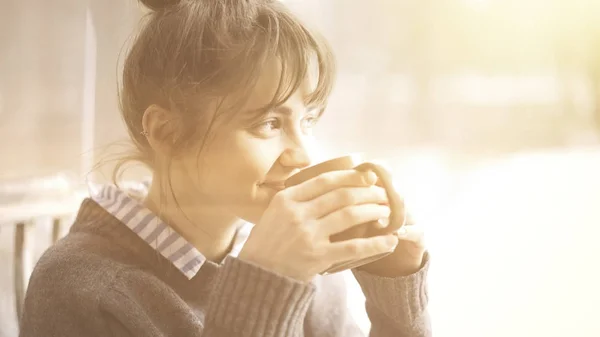 Joven hermosa mujer con un suéter gris está disfrutando de su té en un café y soñando despierto. Bengala . — Foto de Stock