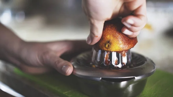 A hand squeezing juice from an orange on a manual glass squeezer. — Stock Photo, Image