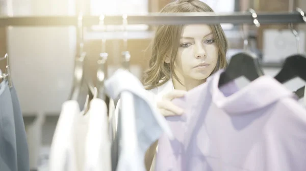 Une femme aux cheveux bruns choisit des vêtements à acheter. Boutique de créateurs . — Photo