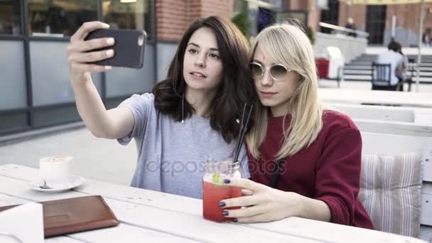 Δύο φίλες κάνουν μια selfie σε μια υπαίθρια καφετέρια — Αρχείο Βίντεο