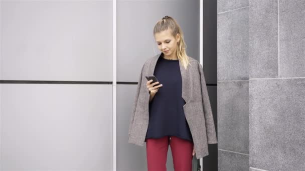 Mujer rubia atractiva con teléfono inteligente fuera — Vídeos de Stock
