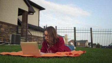 Genç kız ile bir dizüstü bilgisayar çim üzerinde yalan