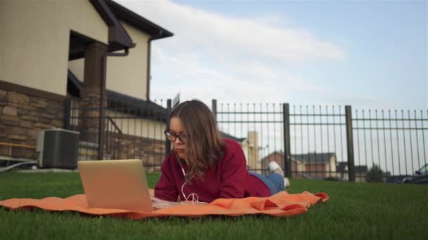 Tiener meisje liggend op het gras met een laptop — Stockvideo