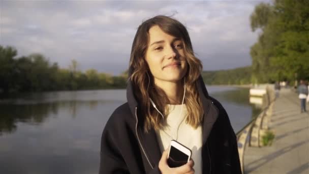 Relaxed young woman listening to music and dancing near a river — Stock Video