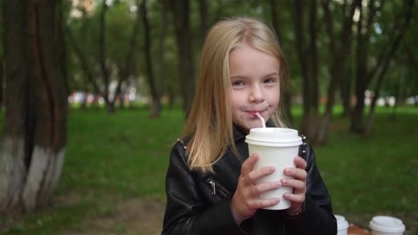 Süßes kleines Mädchen trinkt Limo in einem Park — Stockvideo