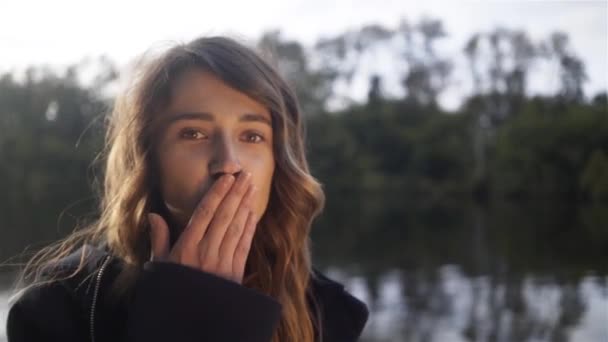 Νεαρό κορίτσι στέλνει ένα φιλί αέρα με τη φωτογραφική μηχανή σε ένα ποτάμι, μια βάρκα — Αρχείο Βίντεο