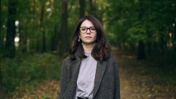 Calm businesswoman in glasses walking in an autumn forest — Stock Video