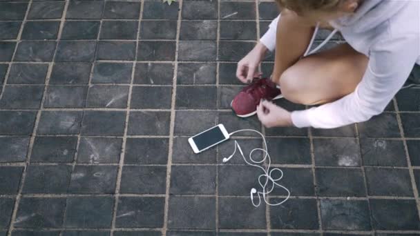 Bovenaanzicht van een jogger vrouw haar schoenveter koppelverkoop en beginnen te lopen — Stockvideo