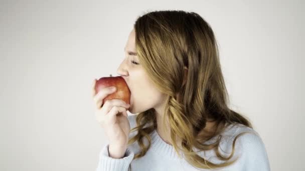 Femme aux cheveux blonds mordant une pomme rouge et flirtant — Video