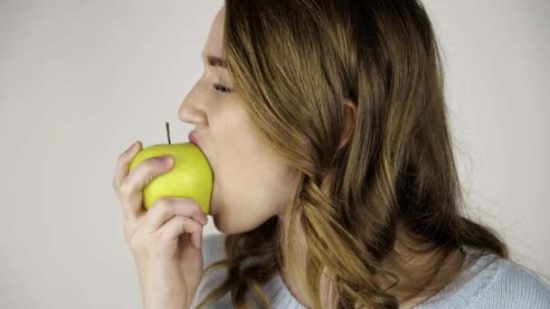 Светловолосая женщина кусает зеленое яблоко и облизывает губы — стоковое видео