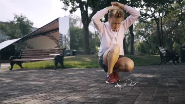 Mujer corredora usando una banda de pelo y empezando a correr en un parque — Vídeos de Stock