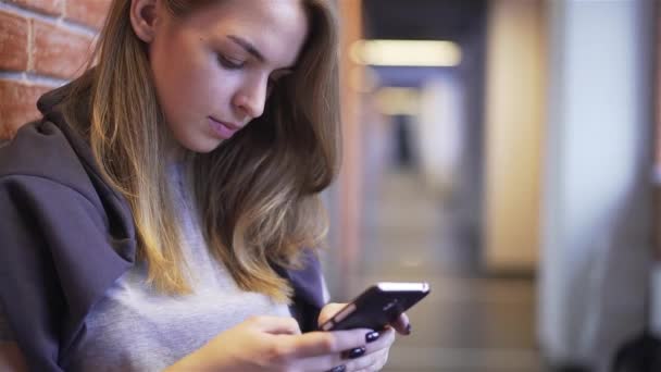 Belle jeune fille textos près d'un mur de briques — Video