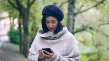 Çekici Asyalı kadın ile bir smartphone bir sonbahar Park
