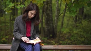 Sakin esmer kadın bir sonbahar Park bir kitap okuma