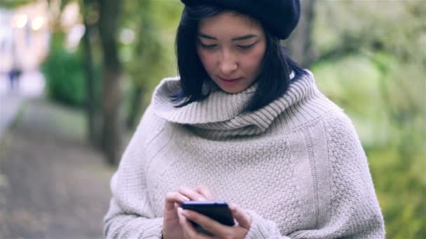 가 공원에 스마트폰으로 서핑 하는 아름 다운 아시아 여자 웹 — 비디오