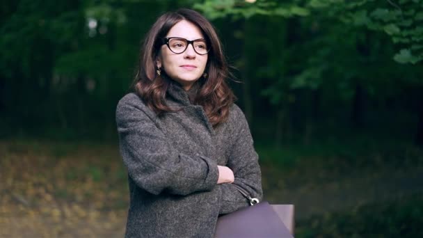 Ruhige Geschäftsfrau mit Brille lächelt im herbstlichen Wald — Stockvideo