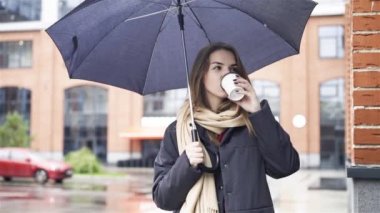 Düşünceli kadın kahve içme şemsiyesi altında
