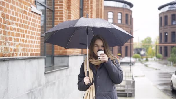 Woman under umbrella drinking coffee — Stock Video