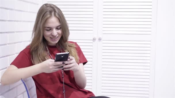 Young woman in red t shirt texting and smiling — Stock Video