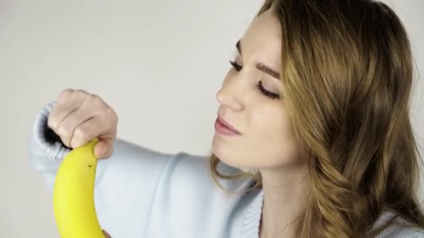 Piękna młoda dziewczyna peeling pysznego banana i jedzenia — Wideo stockowe