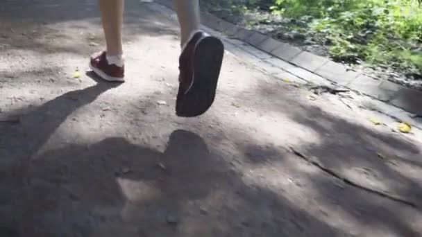 金髪の若い女性が背面の公園でジョギング — ストック動画