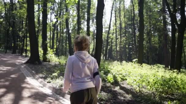 Пан снимок белокурой бегущей в парке — стоковое видео